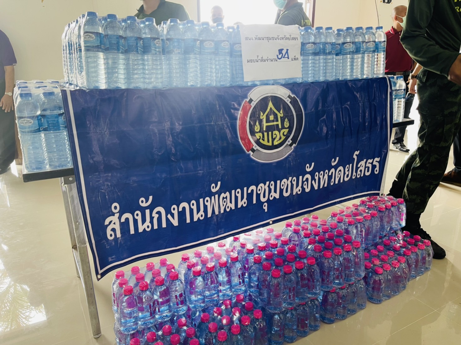 พช.ยโสธรร่วมกับเครือข่าย กทบ. จังหวัดไม่ทิ้งใครไว้ข้างหลัง แบ่งปันน้ำใจ มอบน้ำดื่มให้จุดบริการฉีดวัคซีนป้องกันโควิด-19